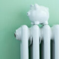 Piggy Bank Balanced On Radiator To Illustrate Energy Costs
